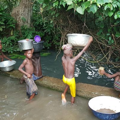 I bambini che raccolgono l'acqua al fiume